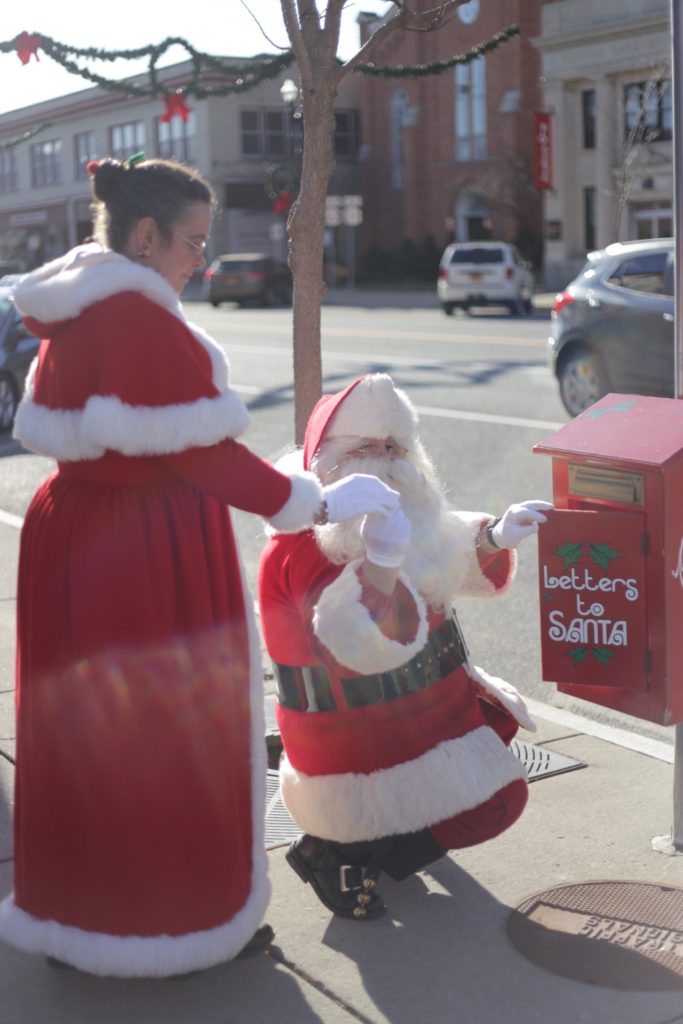 Santa and Mrs. Claus check for letters in the official red mailbox on Main Street Medina, NY.